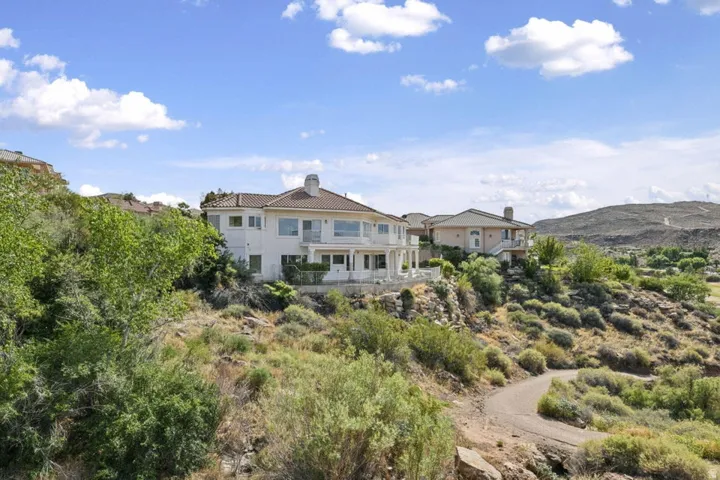 Multi-story residence featuring a tile roof, light-colored exterior, and multiple balconies