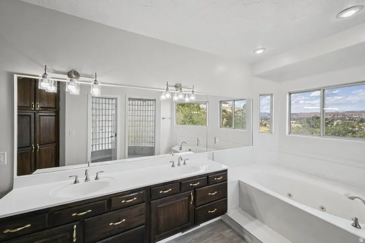 Dual vanity with dark wood-finish cabinetry, built-in storage, and a large soaking tub