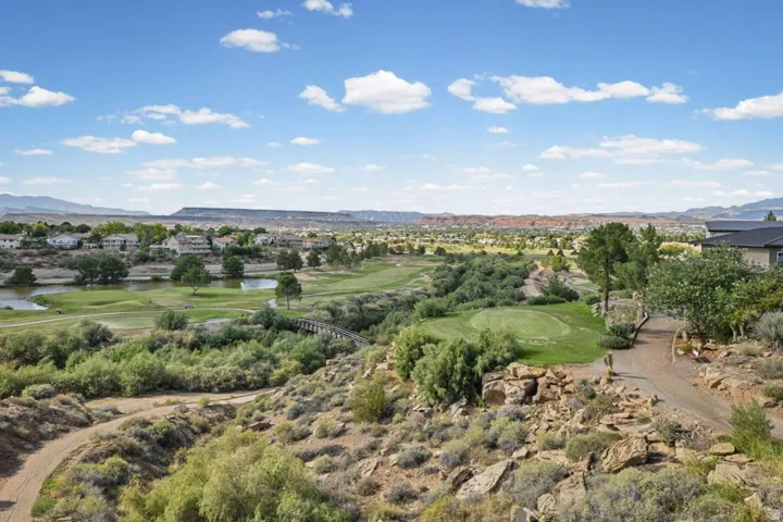 Expansive arid landscaping, golf course frontage, distant residential properties, natural water features, and mountain backdrop