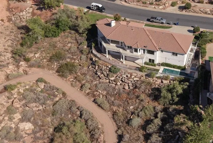 Terracotta tile roof, multiple outdoor balconies, ground-level patio, and an inground pool with surrounding hardscaping