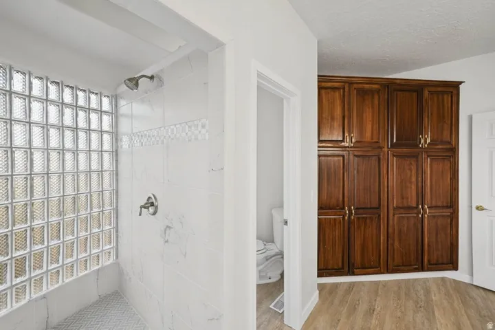 Walk-in shower with glass block wall, tile surround, and herringbone-patterned floor