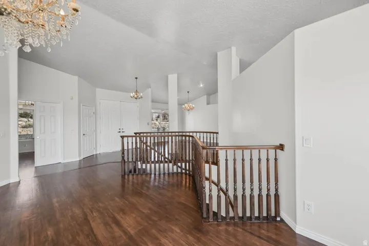 Vaulted ceilings, wood-finish flooring, staircase with wood railing, recessed lighting, and chandelier