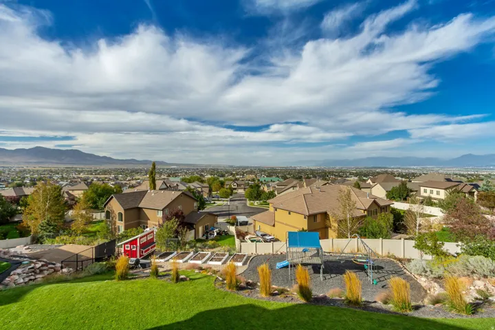 Expansive backyard featuring a manicured lawn, raised garden beds, and an outdoor play structure