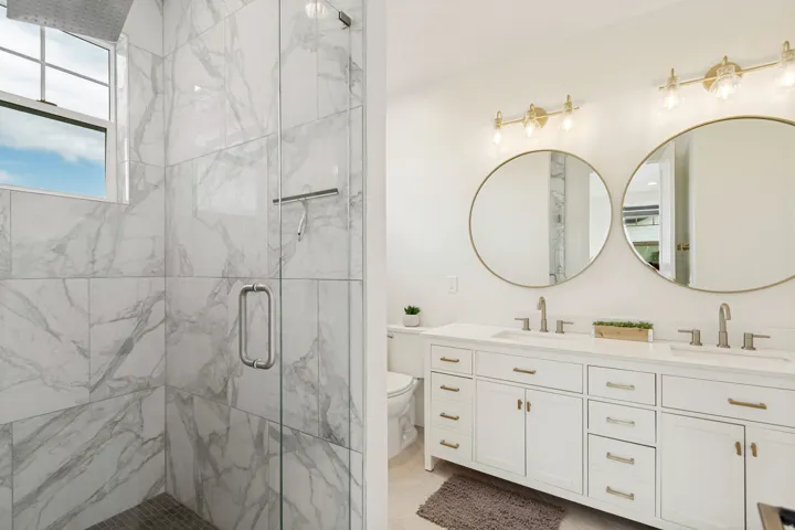 Walk-in shower with marble-look tile surround and glass enclosure