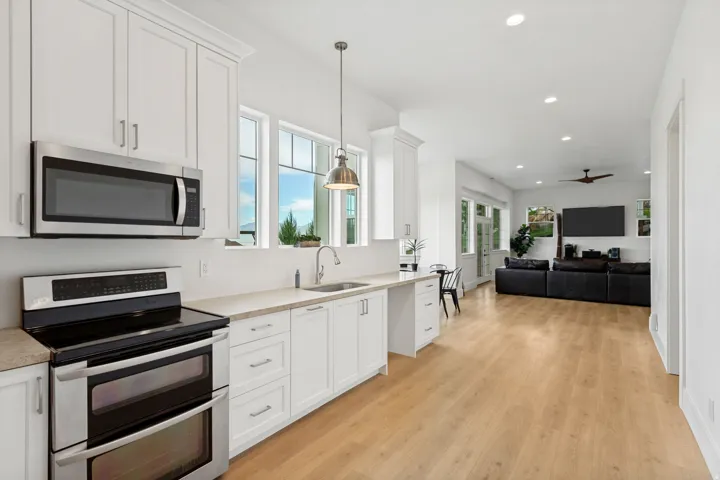 Kitchen featuring stainless steel appliances, white cabinetry, and light wood-finish flooring