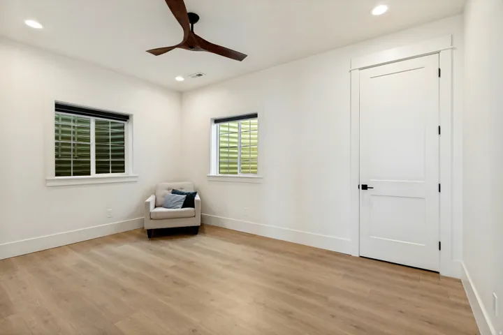Recessed lighting, wood-finish flooring, two-panel interior door with matte black hardware, and a ceiling fan with wood-finish blades