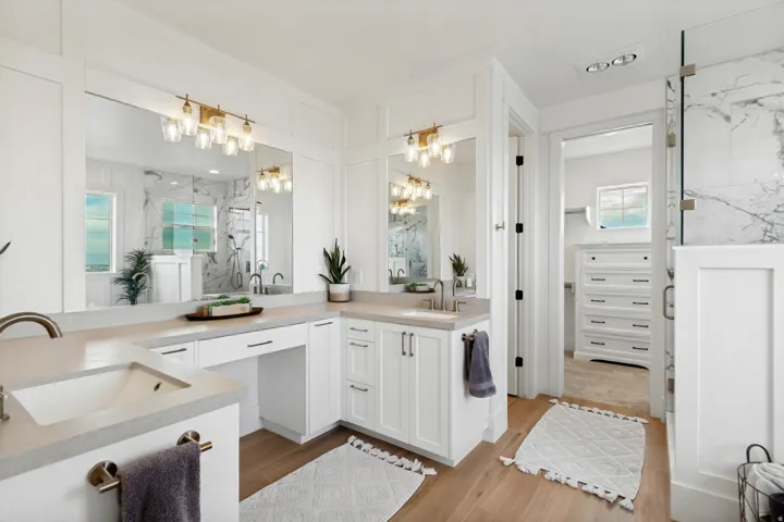 Dual vanity with integrated sinks, light-toned countertops, and brass-finish lighting fixtures