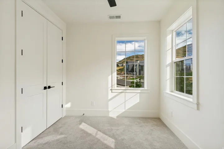Recessed lighting, light gray carpeting, crisp white walls, white trim, and a ceiling fan