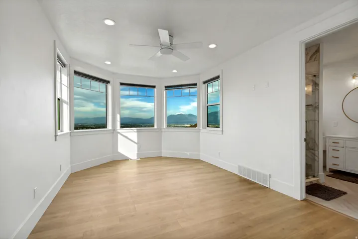 Bay window with four large windows, neutral wood-finish flooring, recessed lighting, and a ceiling fan