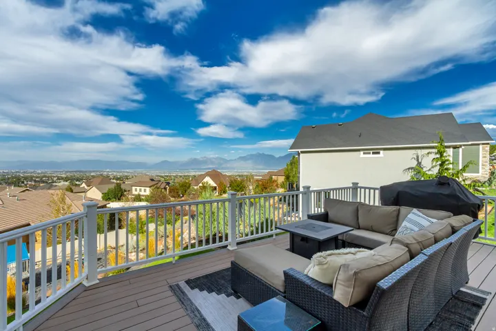 Expansive outdoor deck featuring wood-finish flooring, white railing, and a mountainous backdrop