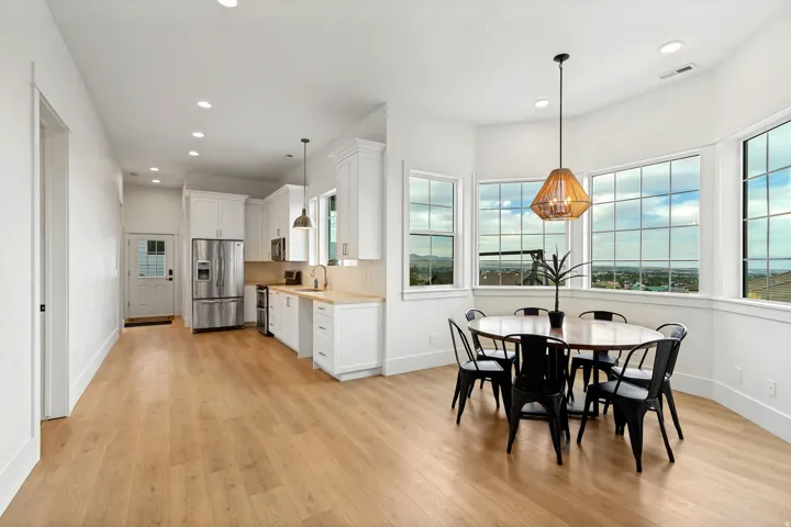 Open concept living space featuring wood-finish flooring, white cabinetry, and stainless steel appliances