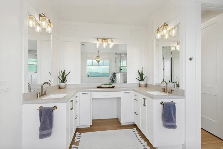 Dual vanities with undermount sinks and brass-finish fixtures, complemented by white cabinetry and light-toned countertops