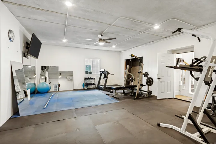 Recreation room featuring rubber floor tiling, white painted walls, recessed lighting, and a ceiling fan