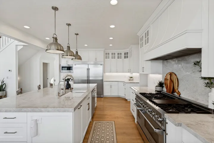 Gourmet kitchen with white cabinetry, stainless steel appliances, and a large center island with an undermount sink