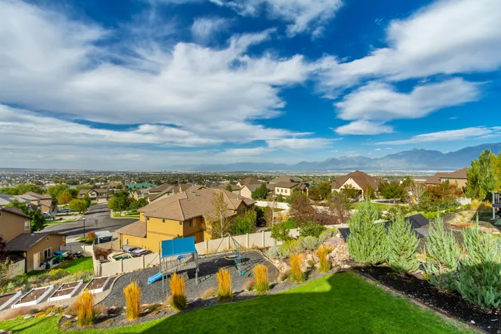 Expansive landscaped yard with a manicured lawn, raised garden beds, and mountain scenery