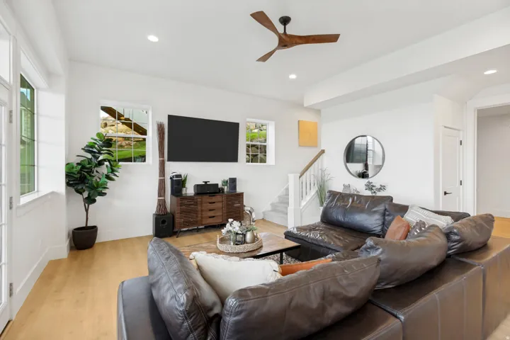 Wood-finish flooring, white walls, multiple windows, recessed lighting, and a modern ceiling fan