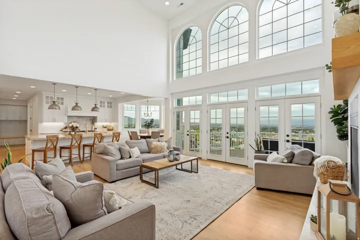 Vaulted ceilings, expansive arched windows, multiple sets of French doors, wood-finish flooring, and a kitchen island with pendant lighting