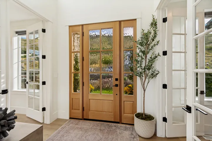 Warm wood-finish entry door with textured glass panels and side lights