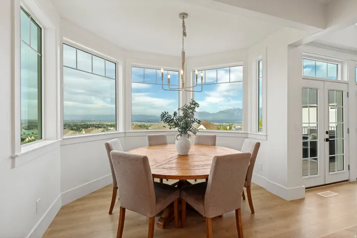 Bay window dining area with wood-finish flooring, a contemporary chandelier, and French doors