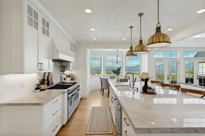 White cabinetry with integrated range hood, stainless steel gas range, stone countertops, wood-finish flooring, and recessed lighting
