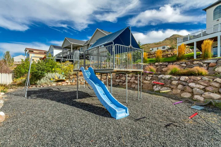 Recreational play structure with slide, swing set, and climbing elements on a dark gravel surface