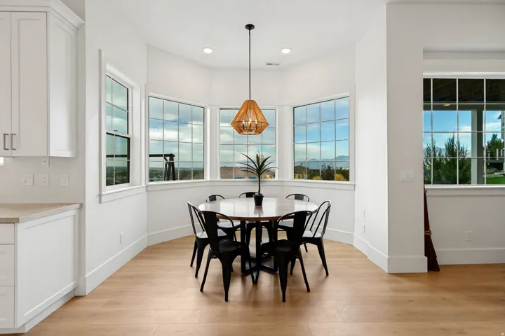 Bay window dining area with wood-finish flooring, recessed lighting, and a decorative pendant light fixture