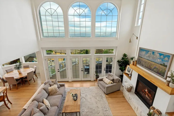 Vaulted ceilings with arched windows, multiple sets of French doors, a built-in fireplace with a stone surround, and wood-finish flooring