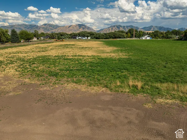 Expansive undeveloped land with varied ground cover, distant mountains, and scattered residential structures