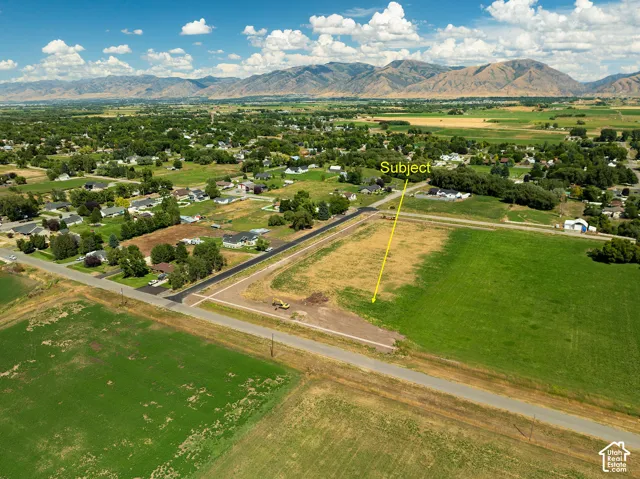 Expansive land lot with established surrounding community, paved road access, and distant mountain scenery
