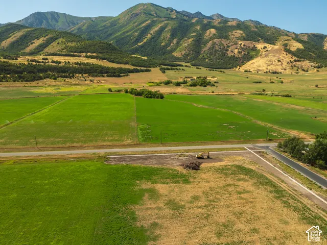 Expansive lot with mountain backdrop, bordered by paved road and agricultural fields