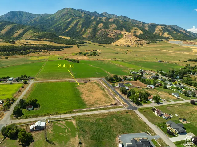 Expansive land parcel with surrounding green fields and mountainous terrain