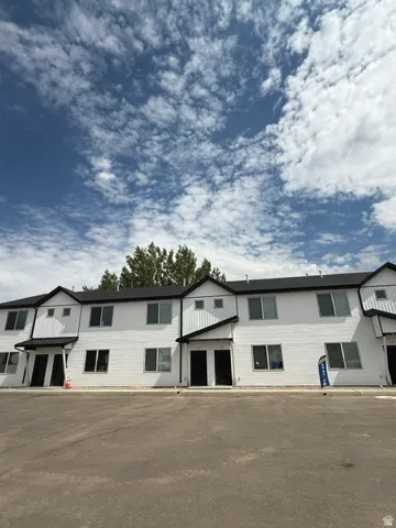 Modern townhome exteriors featuring white siding, black-framed windows, and dark-colored entry doors with small awnings