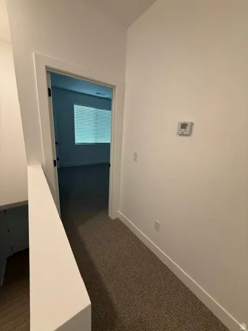Neutral-toned carpet flooring, white walls, modern thermostat, and white trim throughout
