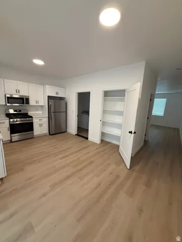 Modern kitchen featuring stainless steel appliances, white cabinetry, recessed lighting, and wood-finish flooring