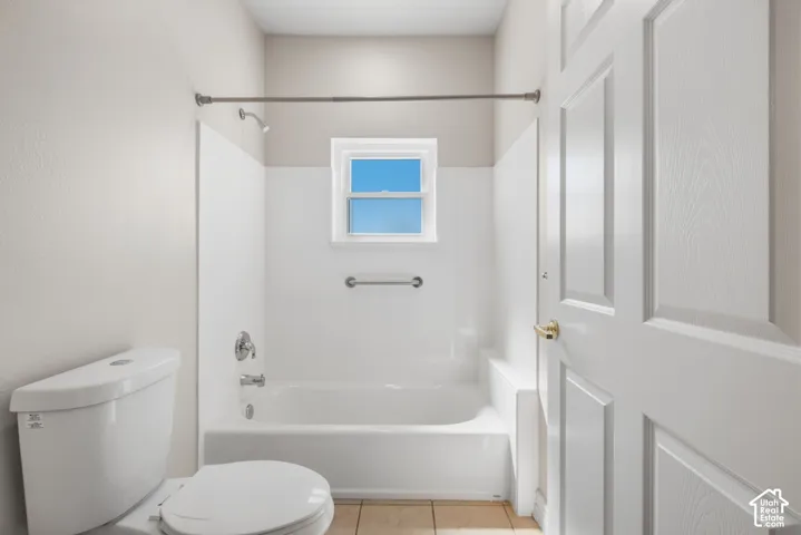 Bathroom featuring a white bathtub, ceramic tile flooring, a window, and a paneled door