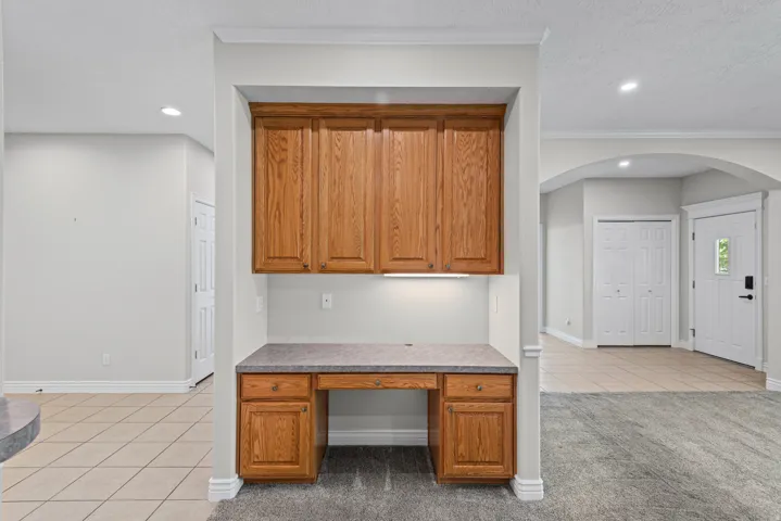 Built-in desk area with wood cabinetry, integrated lighting, and a durable countertop