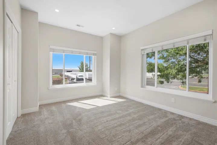 Plush carpet flooring, recessed lighting, and bright windows with included blinds