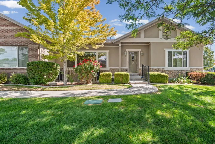 Stucco and brick facade with stone detailing, a prominent front entry with a decorative door, an adjacent window with trim, and a manicured lawn