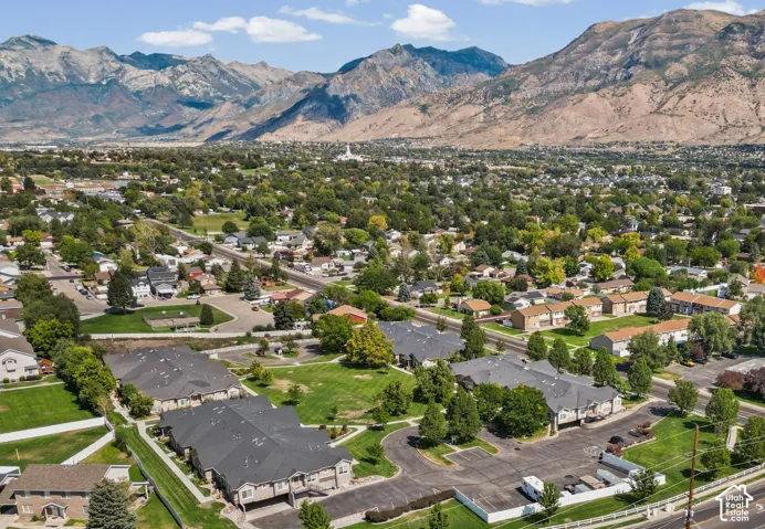 Aerial overview showcasing expansive mountain ranges, an established neighborhood, and multiple multi-unit residential buildings