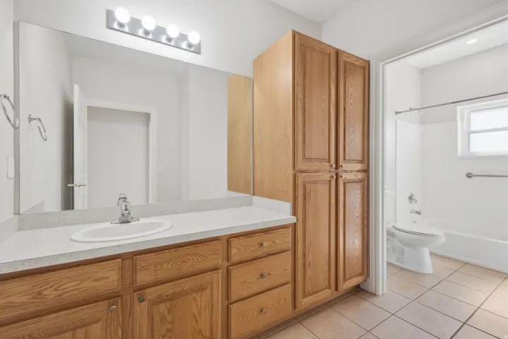 Bathroom featuring a vanity with an integrated sink, laminate countertop, and wood cabinetry