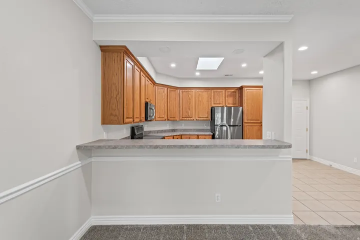 Kitchen with wood cabinetry, stainless steel appliances, and a skylight