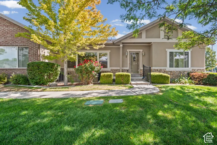 Stucco and brick facade with stone detailing, a prominent front entry with a decorative door, an adjacent window with trim, and a manicured lawn