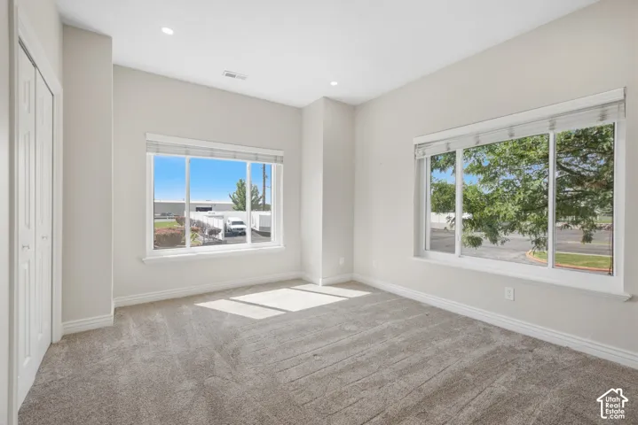 Plush carpet flooring, recessed lighting, and bright windows with included blinds