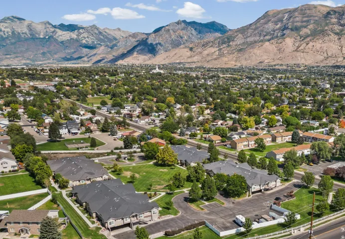 Aerial overview showcasing expansive mountain ranges, an established neighborhood, and multiple multi-unit residential buildings