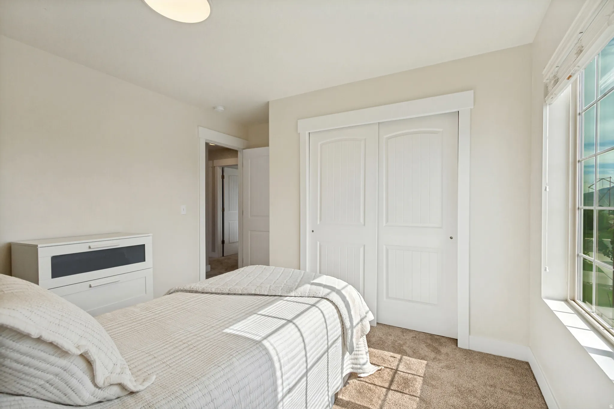 Carpeted flooring, white trim, a window with grid panes, and a closet with bifold doors