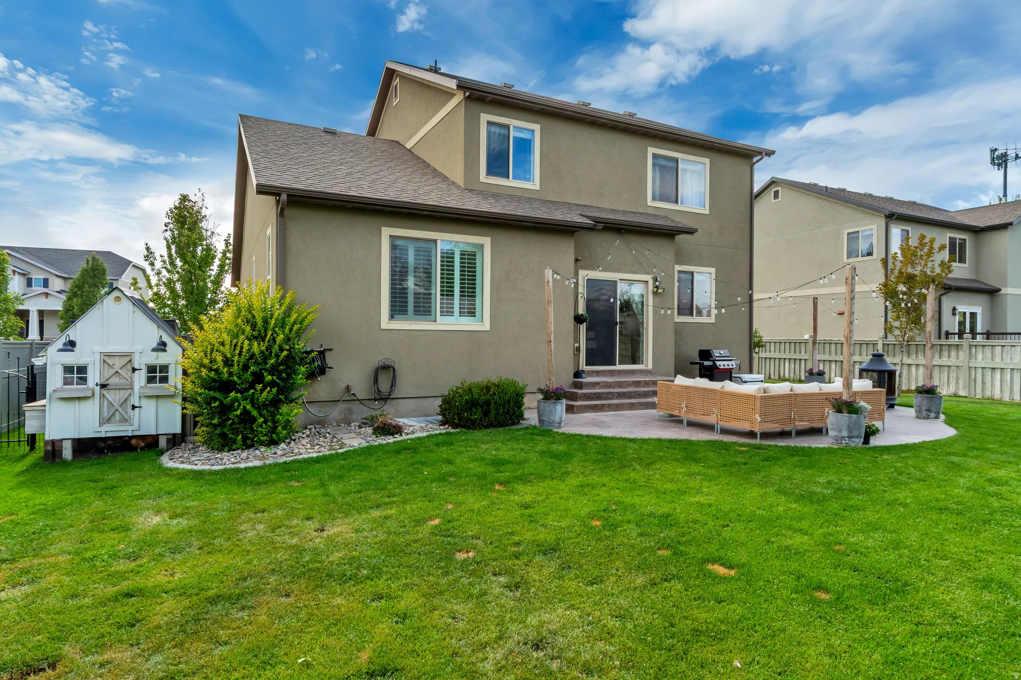 Expansive green lawn with a white shed structure, a built-in paved patio, and sliding glass door access to the interior