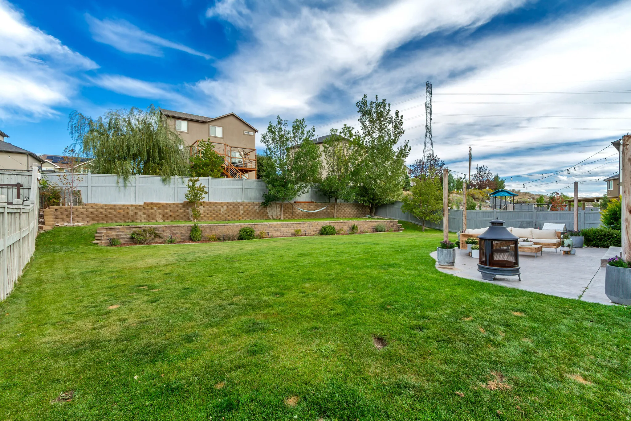 Expansive backyard featuring a manicured lawn, a large paver patio, and retaining walls