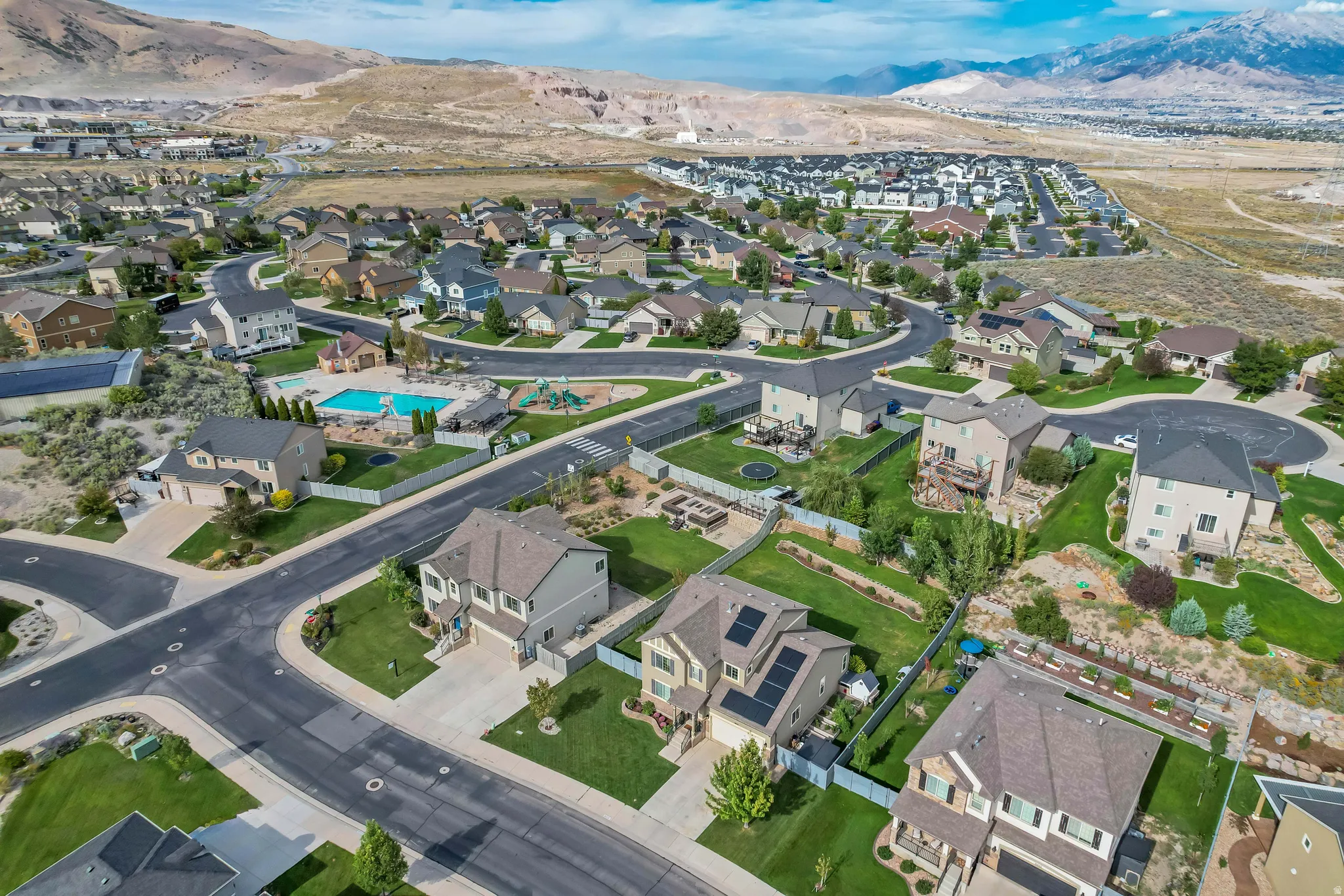 Residential community featuring single-family homes, paved roads, and a community pool area with a playground
