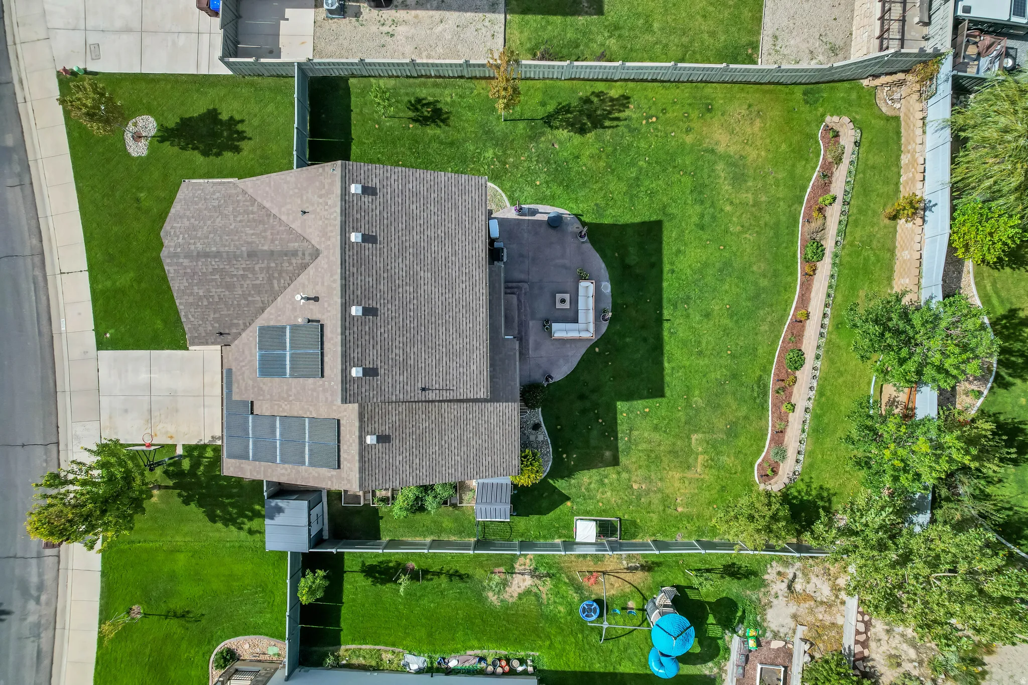Expansive rear yard with a paved patio, manicured lawn, and landscaped garden bed