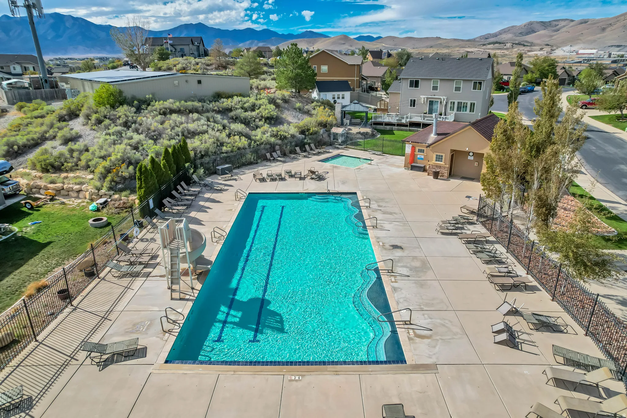 Expansive community pool with a dedicated lap lane, a separate spa, a pool house with stone accents, and a surrounding concrete deck with lounge areas